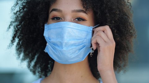 African ethnic woman takes off her protective mask, smiles, breaths in deeply, rejoices at end of flu epidemic. Foreign student gets freedom of movement world feeling relief after quarantine ends