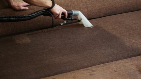 Close-up of washing cleaner cleans the sofa and removes dirt, professional cleaning service.