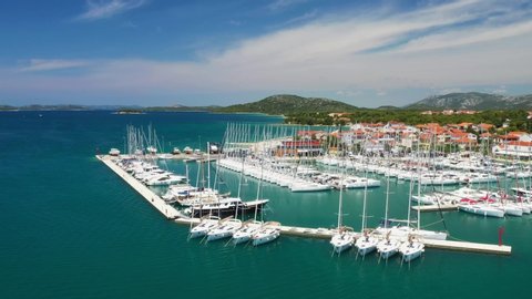 Yachts and boats in marina in town of Pirovac on Adriatic sea in Croatia, drone footage circle view
