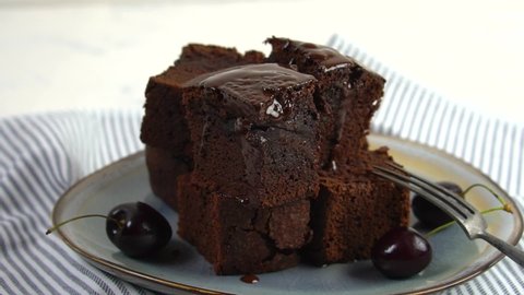 Brownie cake.Dark chocolate pours on the cake. Cakes with chocolate icing on a white slate. Chocolate dessert on a plate with hot chocolate and fruit.