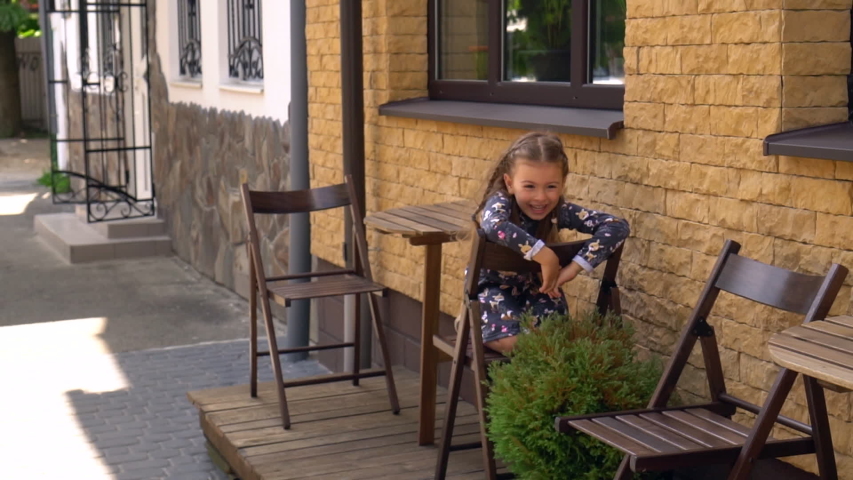 Child in cafe outdoor post pandemic. Little girl in cafe on the street.