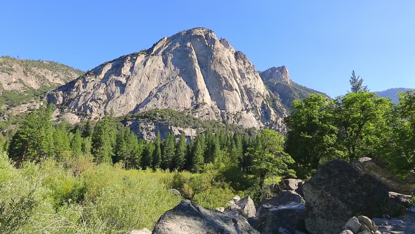 Panorama of Zumwalt Meadows hiking in Kings Canyon National Park, a large grassland in the forest with wildflowers with the surrounding towering cliffs of Kings Canyon.