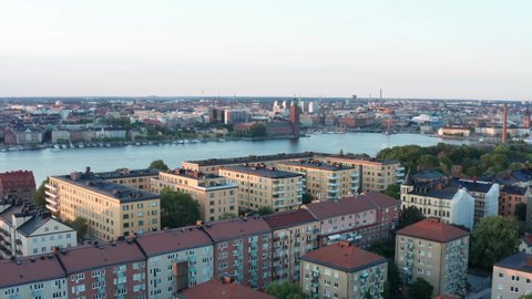 Late summer afternoon in Stockholm, Sweden. Aerial drone view from above rooftops, buildings, moving towards City Hall, Riddarfjärden, the sea of Mälaren, and the Old Town.