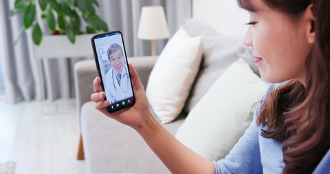 Telemedicine concept - Asian elder male doctor is on the phone to have video chat with patient at home