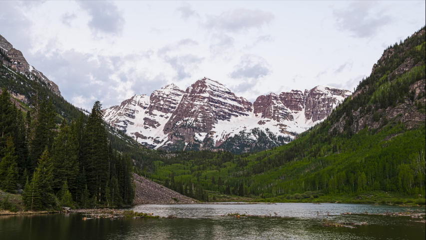 Maroon Bells in Aspen, Colorado with clouds at dawn sunrise with rocky mountain peak and lake reflection in summer timelapse time lapse and water ripples