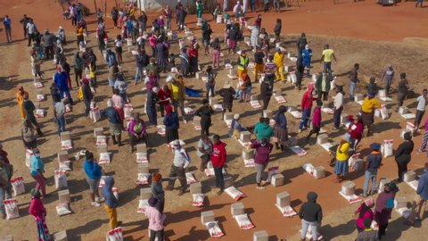 AFRICA,SOUTH AFRICA,CIRCA 2020.  Aerial view of Black African people social distancing receiving food parcels in a poverty stricken informal settlement during lockdown, Covid-19 Coronavirus pandemic