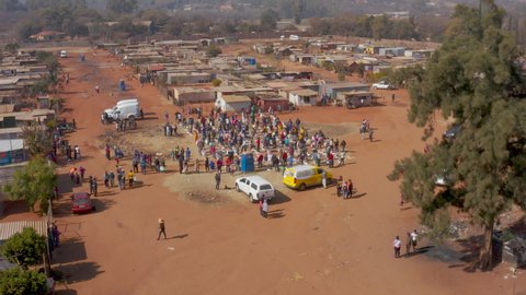 AFRICA,SOUTH AFRICA,CIRCA 2020.  Aerial view of Black African people social distancing receiving food parcels in a poverty stricken informal settlement during lockdown, Covid-19 Coronavirus pandemic