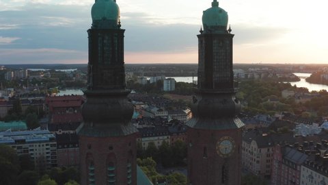 Flying through church towers in Stockholm, Sweden. A summer evening with an aerial view above an urban city with rooftops and the sea of Mälaren and Baltic Sea.