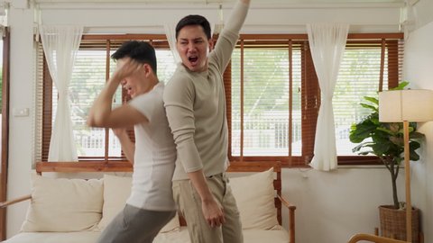 LGBT concept, Asian gay couple  just married homosexual couple  having fun sway dancing together in living room. Men raise hand and happy smile, enjoy music song at home. Happy gay couple portrait indoor at house