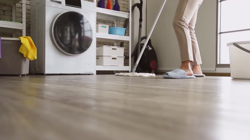 Young Asian woman in casual outfit doing chores housework using dust mop sweeping to clean floor in modern room at home | Shutterstock HD Video #1056131396