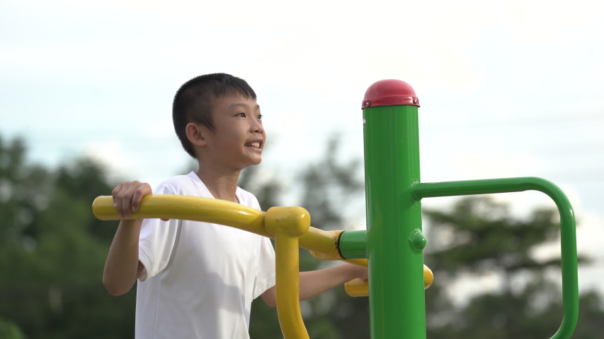 Kids playing and exercing on public outdoor gym park, boy children holding equipment and smile to enjoy play and exercise for good health for outside reaction on blurred background, Asian kids child