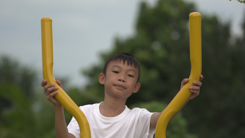 Kids playing and exercing on public outdoor gym park, boy children holding equipment and smile to enjoy play and exercise for good health for outside reaction on blurred background, Asian kids child
