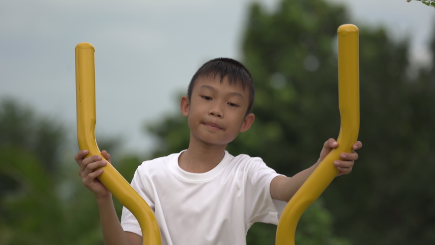 Kids playing and exercing on public outdoor gym park, boy children holding equipment and smile to enjoy play and exercise for good health for outside reaction on blurred background, Asian kids child
