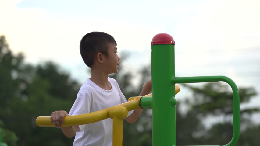 Kids playing and exercing on public outdoor gym park, boy children holding equipment and smile to enjoy play and exercise for good health for outside reaction on blurred background, Asian kids child