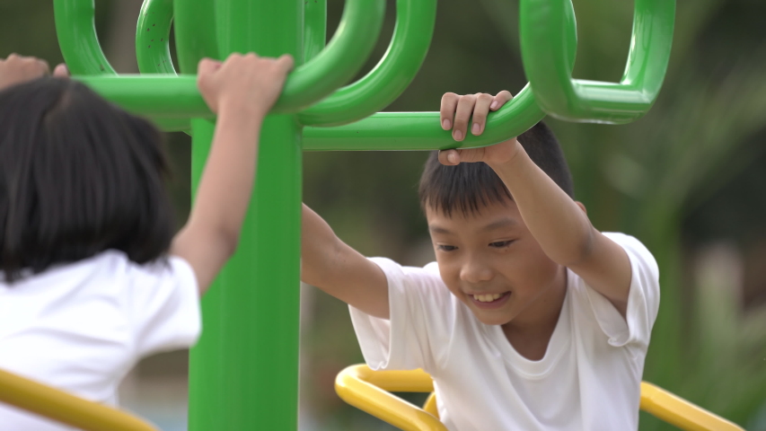 Kids playing and exercing on public outdoor gym park, boy girl children holding equipment and smile enjoy play and exercise for good health for outside reaction on blurred background, Asian kids child