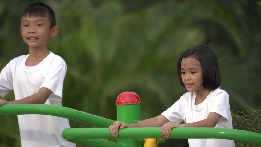 Kids playing and exercing on public outdoor gym park, boy girl children holding equipment and smile enjoy play and exercise for good health for outside reaction on blurred background, Asian kids child