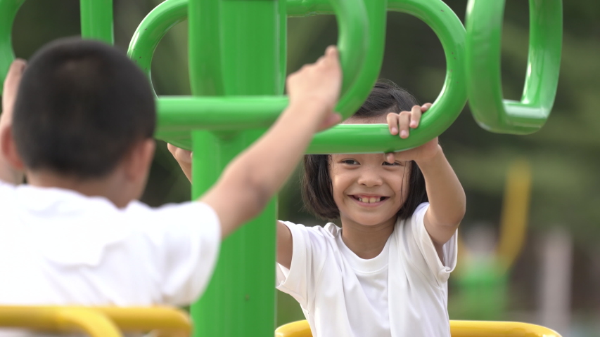 Kids playing and exercing on public outdoor gym park, boy girl children holding equipment and smile enjoy play and exercise for good health for outside reaction on blurred background, Asian kids child
