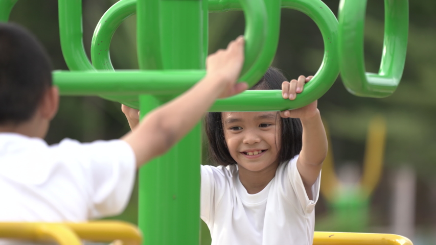 Kids playing and exercing on public outdoor gym park, boy girl children holding equipment and smile enjoy play and exercise for good health for outside reaction on blurred background, Asian kids child