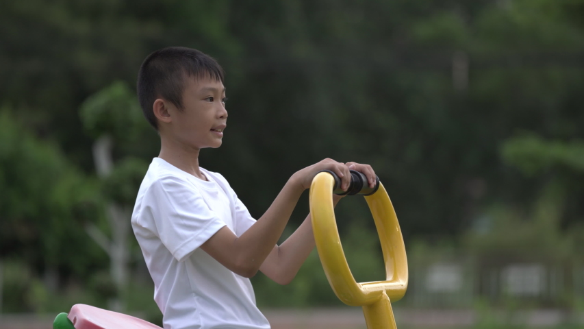 Kids playing and exercing on public outdoor gym park, boy children holding equipment and smile to enjoy play and exercise for good health for outside reaction on blurred background, Asian kids child