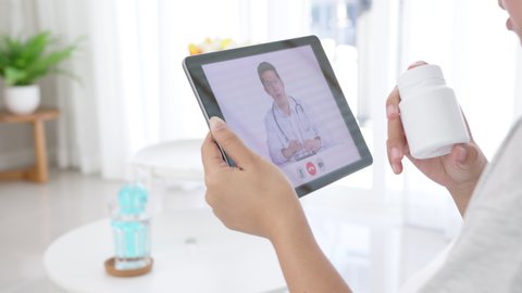 Telemedicine concept close up of asian woman video call with doctor at living room home. Patient girl consulting with general practitioner application computer tablet. Doctor and Consultant online