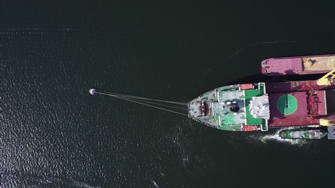 Top view of cargo bulker lie on anchor in with barges on both sides of vessel. Aerial of underway ship to ship transfer operation, STS of coarse grain. Gantry crain load wheat on freighter hold