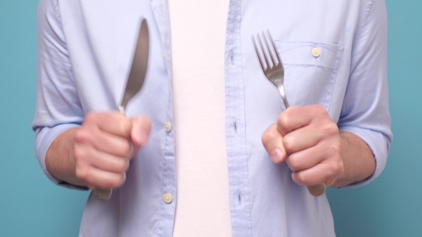 two hands trembling holding fork and knife being hungry