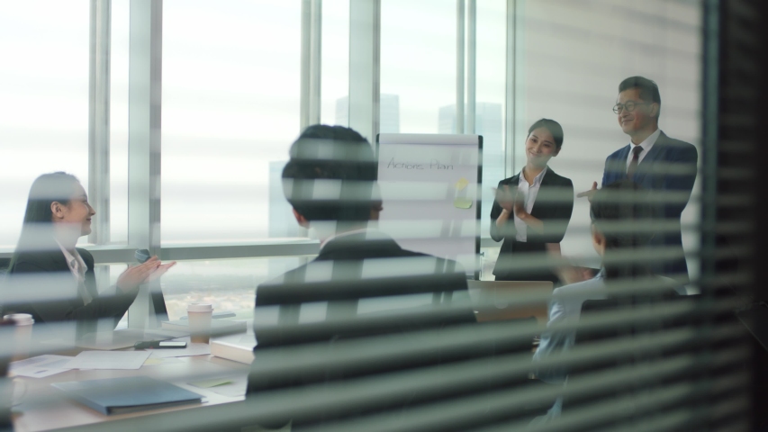 Asian manager introducing new team member during staff meeting in modern office conference room | Shutterstock HD Video #1056146558
