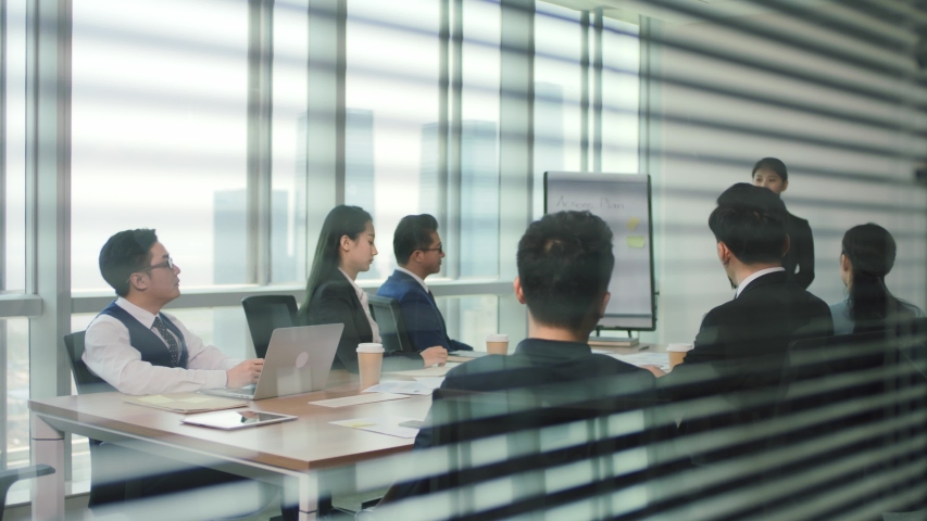 junior asian executive presenting business plan to team during staff meeting in modern office conference room Royalty-Free Stock Footage #1056146798