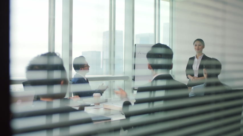 Junior asian executive presenting business plan to team during staff meeting in modern office conference room | Shutterstock HD Video #1056146798