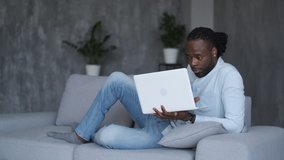 Using ChatGPT.Chat GPT.Artificial Intelligence.Online learning, African american student, distance lesson, webinar conference. African American man lies on a sofa and holds a laptop 
