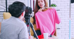 Young Asia couple selling fashion clothes online by live streaming with digital camera.