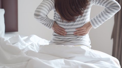Woman suffering from back ache on the bed in the morning, healthcare and problem concept