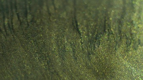 Green gold metallic paint fluid macro background. Real liquid oil paint with shiny glitter particles. Marble texture in motion 