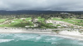 4K cinematic drone shot of green golf club, scenic tropical white sandy beach and beautiful shore of light green Pacific ocean, California, USA. Summer nature video. Sunny day with mountain landscape