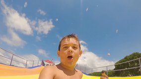 Impressive selfie view of a happy caucasian 8 year old boy having fun sliding down in an water park on a sunny day in summer. - Powered by Shutterstock - Get 15% off with code: PIKWIZARD15
