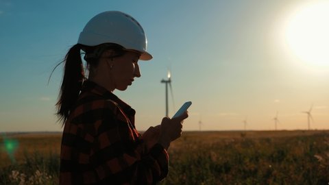Woman engineer working in wind turbine electricity industrial at sunset.
