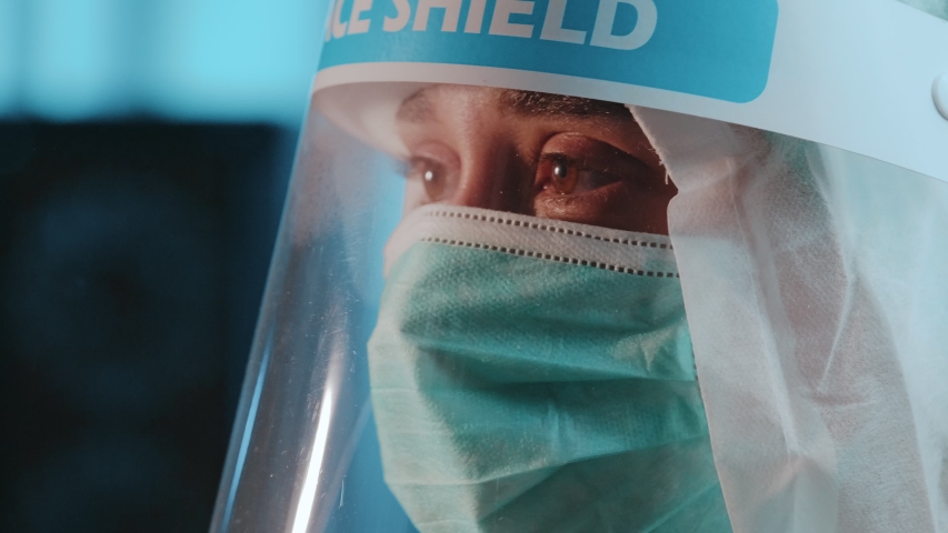 Portrait of female nurse or doctor looking up with face mask and shield covering her face in medical scientific laboratory during new coronavirus pandemic COVID-19 | Shutterstock HD Video #1056153806