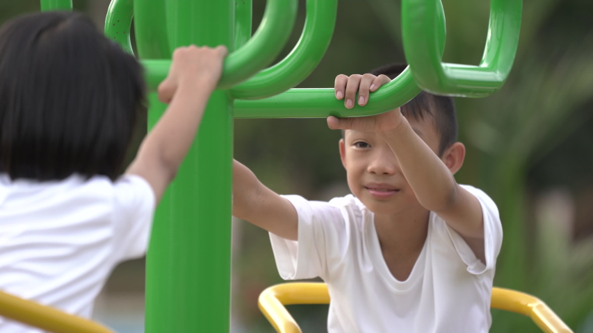 Kids playing and exercing on public outdoor gym park, boy girl children holding equipment and smile enjoy play and exercise for good health for outside reaction on blurred background, Asian kids child
