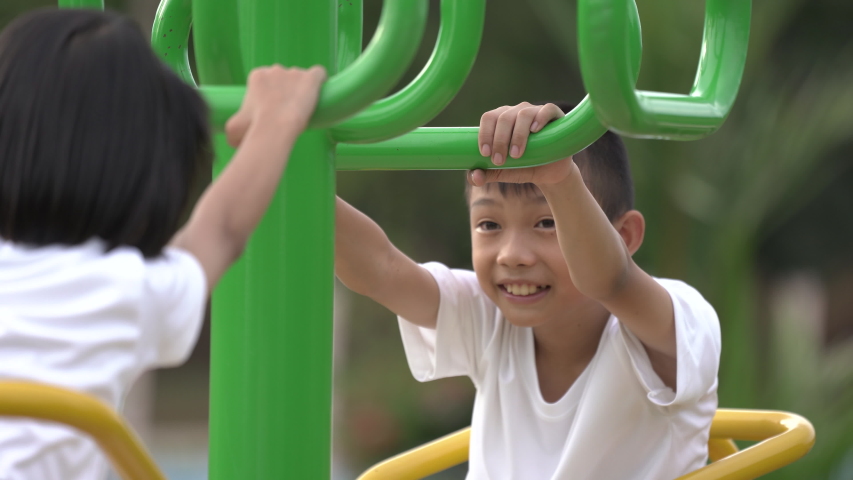 Kids playing and exercing on public outdoor gym park, boy girl children holding equipment and smile enjoy play and exercise for good health for outside reaction on blurred background, Asian kids child