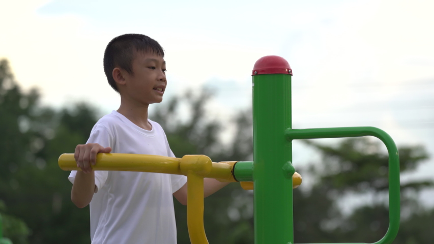 Kids playing and exercing on public outdoor gym park, boy children holding equipment and smile to enjoy play and exercise for good health for outside reaction on blurred background, Asian kids child