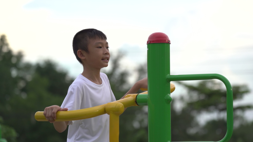 Kids playing and exercing on public outdoor gym park, boy children holding equipment and smile to enjoy play and exercise for good health for outside reaction on blurred background, Asian kids child