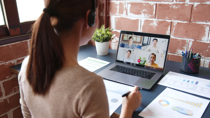 Young Asian businesswoman work at home and virtual video conference meeting with colleagues business people, online working, video call due to social distancing at home office | Shutterstock HD Video #1056163727