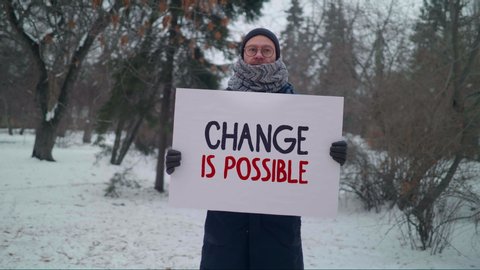 "Change is possible" sign, one man protest, caucasian male activist in a park picket at winter day calls for a change in the political regime in the country