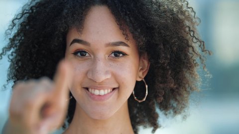 Happy attractive ethnic American pretty student girl pointing finger to camera and inviting to get good education abroad. Beautiful African woman invites you to go to holiday sales discounts in stores