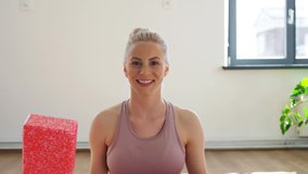 fitness, sport and video blogging concept - woman or blogger with exercise block recording online yoga class in gym or studio