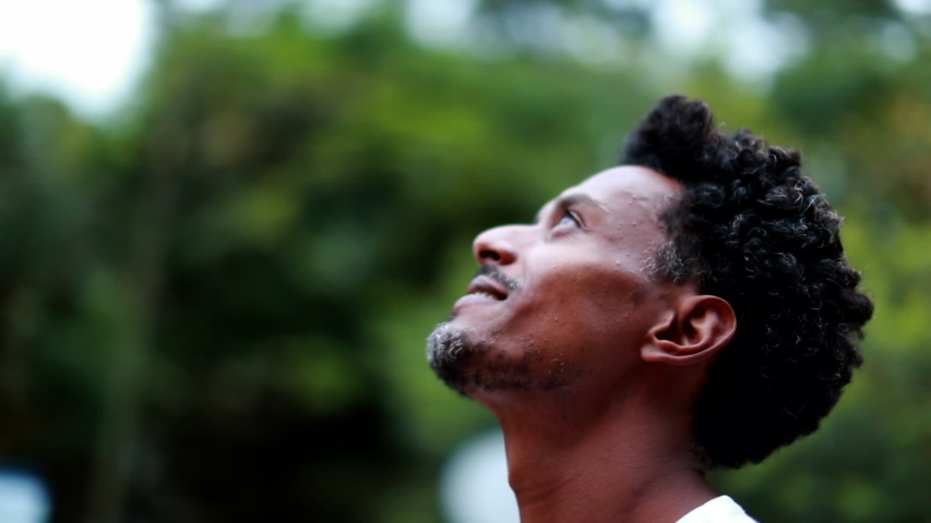 Hopeful African american person looking to the sky with faith and contemplation, man celebrating life | Shutterstock HD Video #1056178220