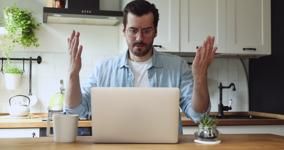 Man sit at table in kitchen feels annoyed having problems with laptop. System error, bad e-mail, negative news, data loss, backup battery issues, password wrong, unsaved, lost info need repair concept