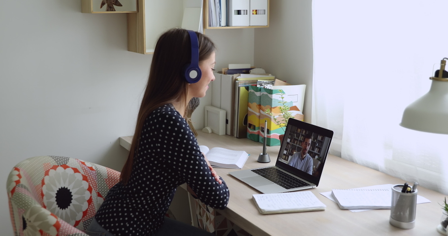 Woman sit at desk wear headphones looks at pc screen talking with teacher distantly by video call, Online tutoring language teaching, colleagues work on common project use video conference app concept Royalty-Free Stock Footage #1056179216