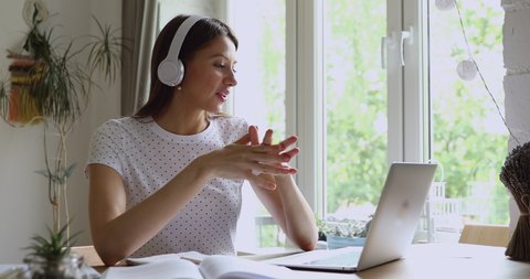 Student girl make notes listen through headphones online tutor studying sit at desk. Friends do high school task by video call, easy comfort communication use modern tech, video conference app concept