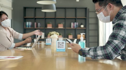 Asian man qr scan seat check in and hand sanitizer before start work at coworking space. Asia employee start work after covid lockdown measure. Shared and flexible office concept. Protection measure